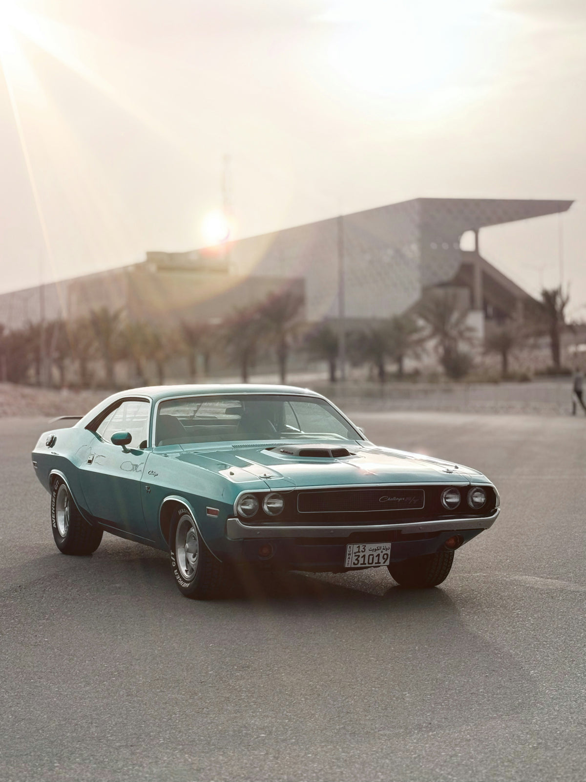Original outdoor photograph of a teal classic Dodge Challenger with three visible tires.