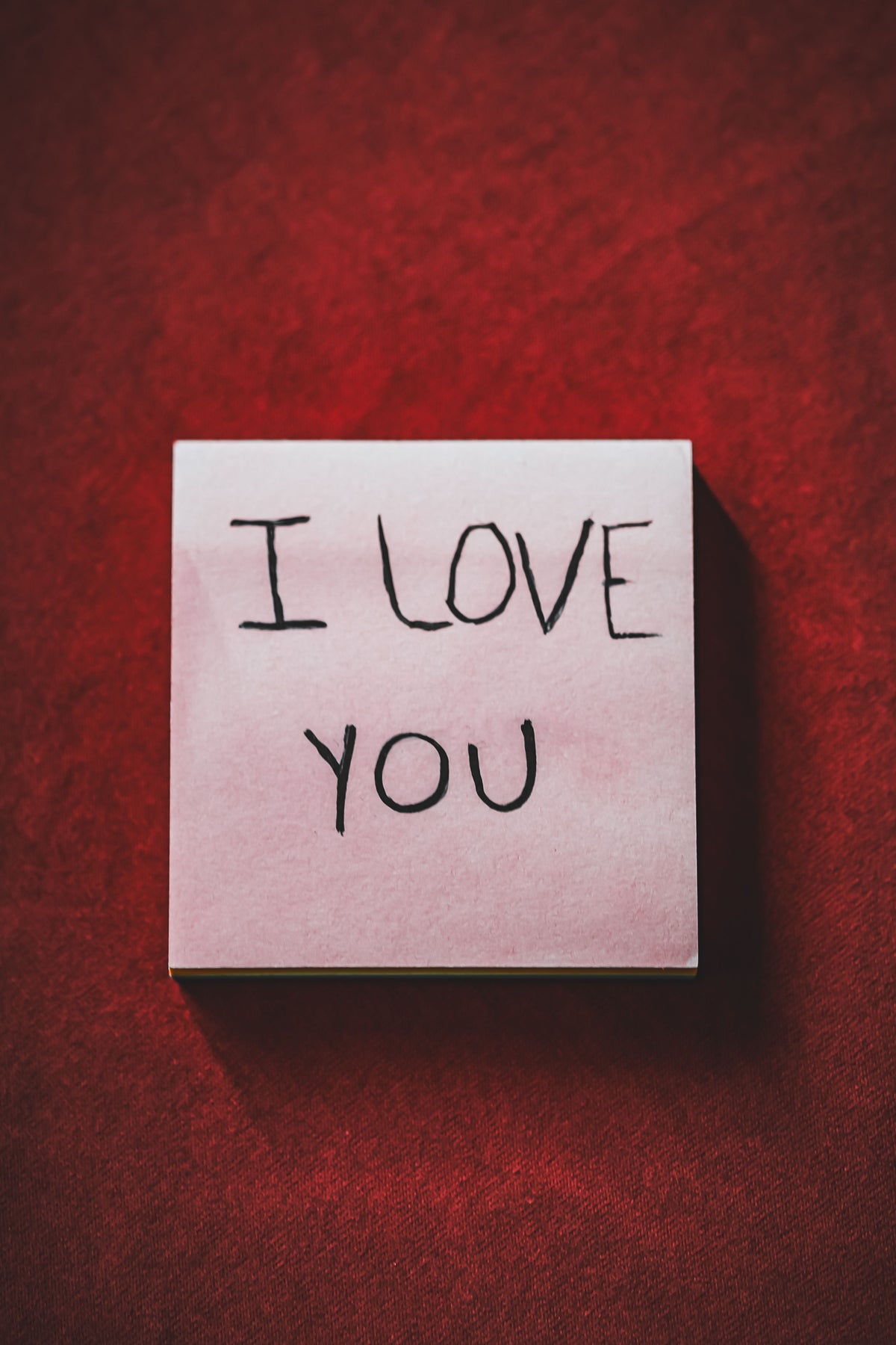 Original photograph of a pink handwritten note against red fabric